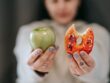 woman showing apple and bitten doughnut